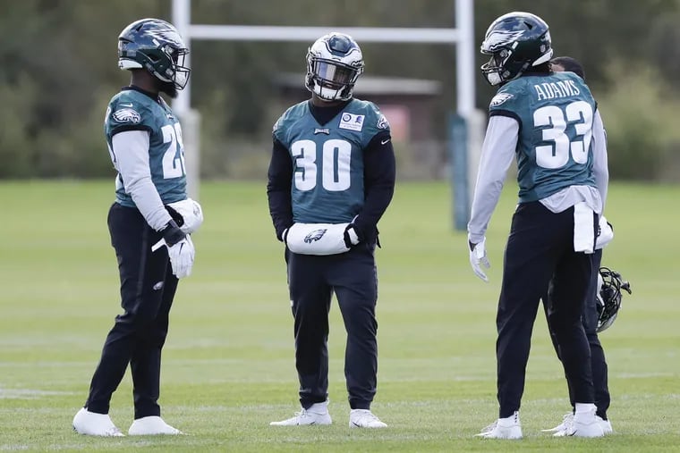 Eagles running backs Wendell Smallwood (left), Corey Clement (center) and Josh Adams gather before the start of practice at the London Irish training ground in Southwest London on Friday, October 26, 2018. YONG KIM / Staff Photographer