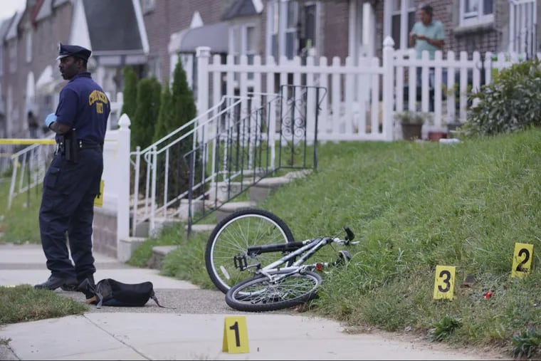 Investigators mark evidence near the victim’s bicycle on Magee Avenue near Bustleton Avenue, Wednesday Oct. 11, 2017, in the Oxford Circle section of Northeast Philadelphia, after police witnessed a teen shoot another teen in the head. According to police an officer witnessed the shooting just before 4:30 p.m. and gave chase of the suspect, apprehending him a block away and recovered a handgun. Police said the victim was transported by officers to Aria-Jefferson Health Torresdale hospital where he was listed in critical condition. (For the Inquirer and Daily News/ Joseph Kaczmarek) .