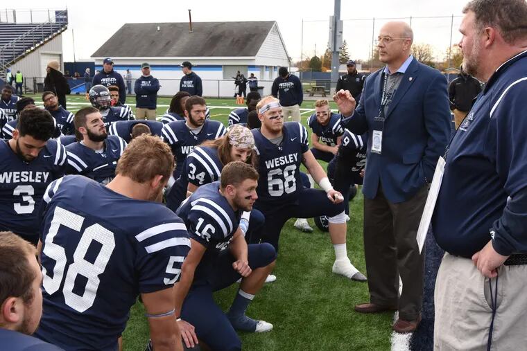 School president Robert Clark speaks with football players at Wesley College in Dover, Del.