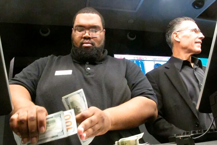 In this Nov. 20, 2018 photo, Lance Weekes, a clerk at the DraftKings sportsbook at Resorts Casino in Atlantic City N.J,. counts money at the betting counter. New Jersey gambling regulators revealed Thursday, Feb. 13, 2019, that gamblers had made $385 million worth of sports bets in the state in January during the NFL playoffs and run-up to the Super Bowl.  (AP Photo/Wayne Parry)