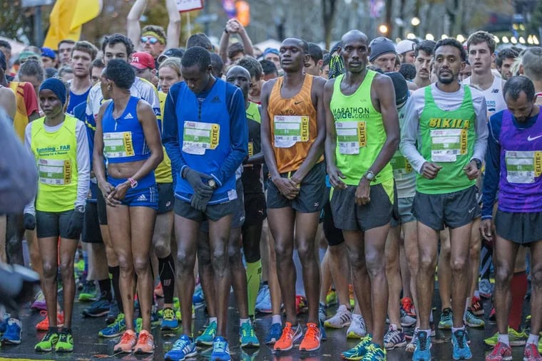 The elite runners of the Philadelphia Marathon try to stay warm as a cold wind blows through at the starting line on Sunday, Nov. 19, 2017.