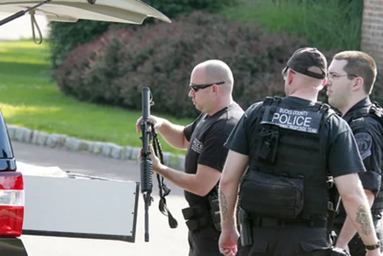 A police officer takes a rifle out of his car Sunday in Doylestown where a man barricaded himself in his home. (Akira Suwa / Staff Photographer)