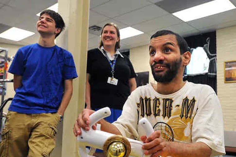 Dennison Perez steers a Wii game at United Cerebral Palsy. With him are student Greg Lobanov, who helped test the adapted controller Perez is using, and Springside physics teacher Ellen Kruger.