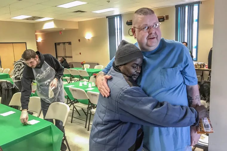 Joe Bednarsky (right) a security officer and volunteer at Bethel A.M.E. Church in Millville, N.J., gets a hug from Sammy Tse after Sammy finished eating at the church’s soup kitchen.