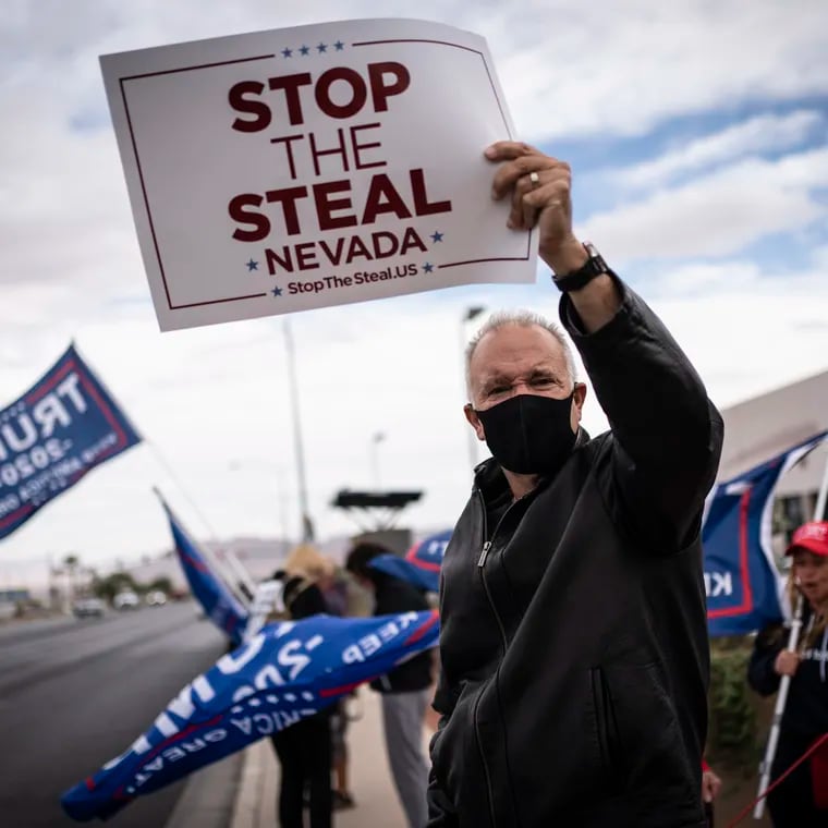 Supporters of President Donald Trump hold signs as they stand outside of the Clark County Elections Department in North Las Vegas on Nov. 7, 2020.