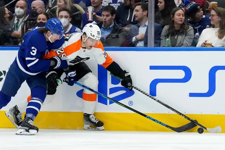 Toronto Maple Leafs defenseman Justin Holl (3) battles Philadelphia Flyers forward James van Riemsdyk (25) for the puck during the first period of an NHL hockey game Tuesday, April 19, 2022 in Toronto.