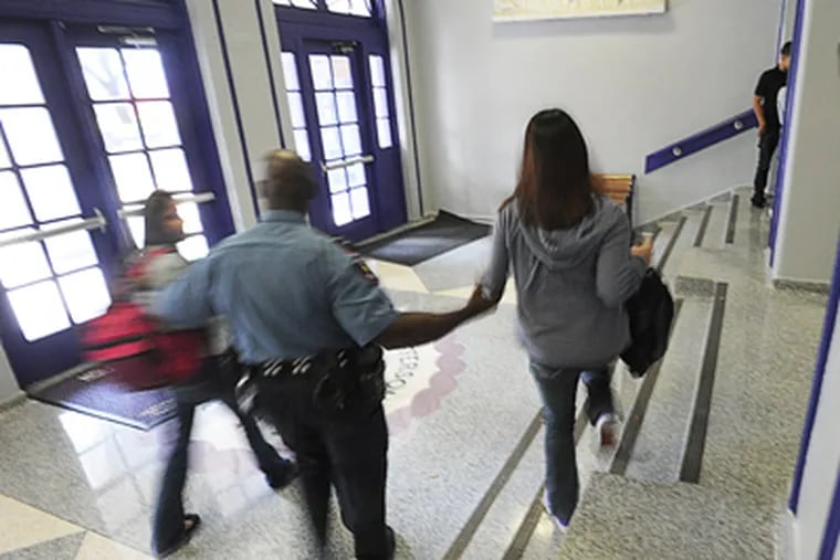 The Houston School District has armed police officers in their schools. Officer Patrick Haywood escorts two students outside after a fight broke out at Jefferson Davis High School in Houston. (Sharon Gekoski-Kimmel / Staff Photographer )