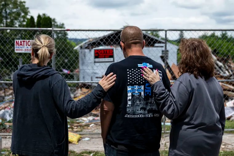 A man identified as Michael Matuzsan, the grandfather of four children killed Thursday night when their house exploded in Pottstown, is comforted by neighbors Saturday as he surveyed the debris from the explosion. Five people were killed and two injured, including Matuzsan's daughter. The cause of the explosion is still under investigation.