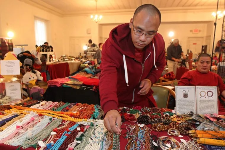 Tibetan monk Tsultrim Dorjee arranges the necklaces and prayer bracelets on his table for sale at a previous Tibetan Bazaar. The 2017 edition opens on Friday, Nov. 24.