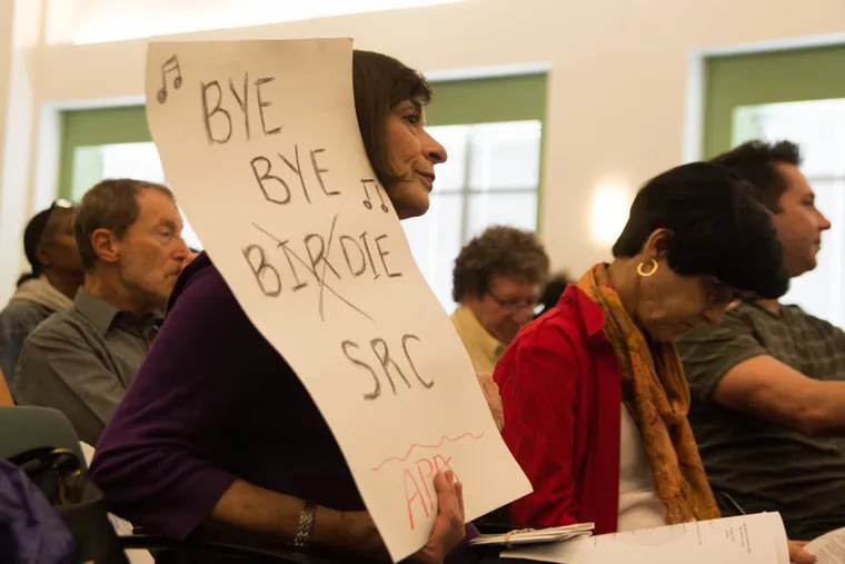 Ilene Poses holds a sign at the SRC meeting Thursday calling for the SRC to be disbanned.
