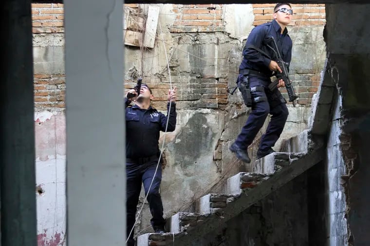FILE - In this Jan. 2, 2019 file photo, Mexican police climb up a set of stairs of a dilapidated building during a shootout with a group of armed criminals in Acapulco, Mexico. Officials say homicides in Mexico rose by 9.7% in the first quarter of 2019 compared to the same period of 2018. President Andres Manuel Lopez Obrador said Monday, April 22, 2019, that he wants to reduce violence through social programs and a new militarized police force known as the National Guard.  (AP Photo/Bernardindo Hernandez, File)
