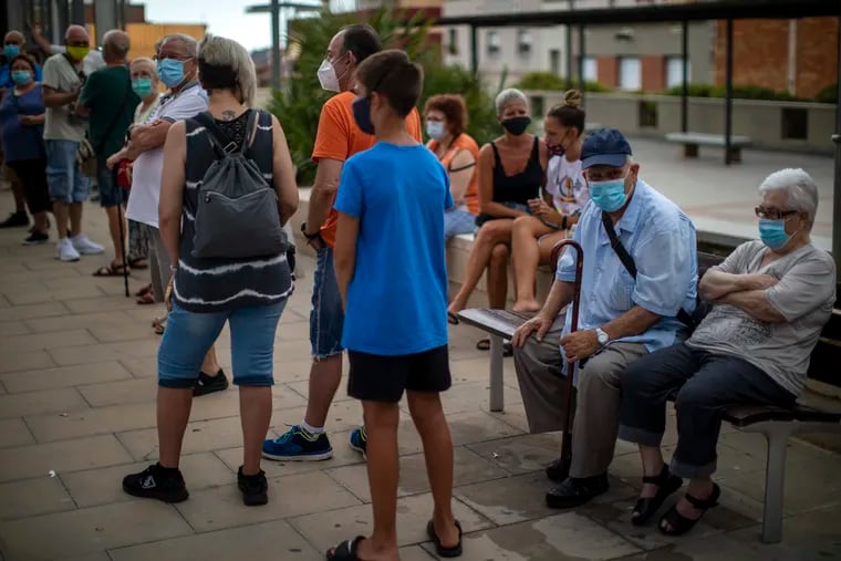 People wearing face masks wait their turn to be called for a PCR test for the COVID-19 on Tuesday outside a local clinic in Santa Coloma de Gramanet in Barcelona, Spain.