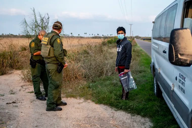 A young man is apprehended by U.S. Customs and Border Protection officials at the U.S.-Mexico border near Mission, Tex., on Feb. 10.