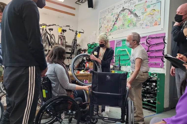 Participants in a workshop from TechOWL's Wheelchair Alliance learn about wheel repair and maintenance at Neighborhood Bike Works in West Philly. The workshops bring together wheelchair users and bike shop workers to learn how to care for wheelchairs.