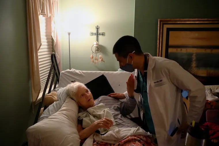 Carol McKenna (left), 75, reaches up to thank nurse practitioner Tarik Khan after he gave her the first dose of a COVID-19 vaccine at her home in South Philadelphia.