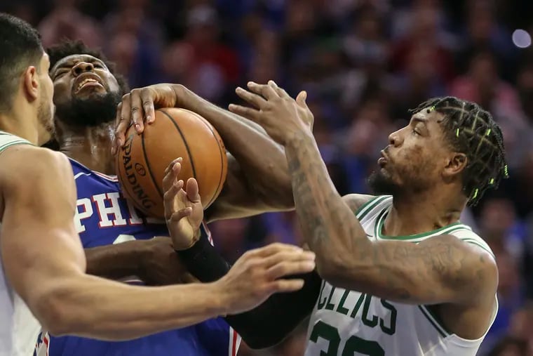 The Sixers' Joel Embiid trying for a rebound between Celtics Enes Kanter, left and Marcus Smart during the  home opener at the Wells Fargo Center.
