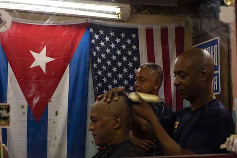 Cuban and U.S. flags hang in Eugenio Lafargue's Havana barbershop. Who isn't so happy? Foreigners, who have had Cuba to themselves. AP