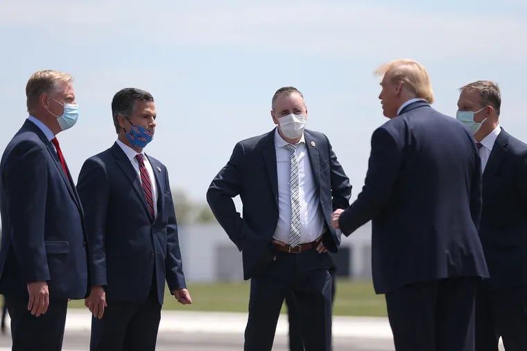 Republican Pennsylvania Rep. Brian Fitzpatrick, center, and other members of Congress greet President Donald Trump as he arrives at Lehigh Valley International Airport on May 14, 2020.