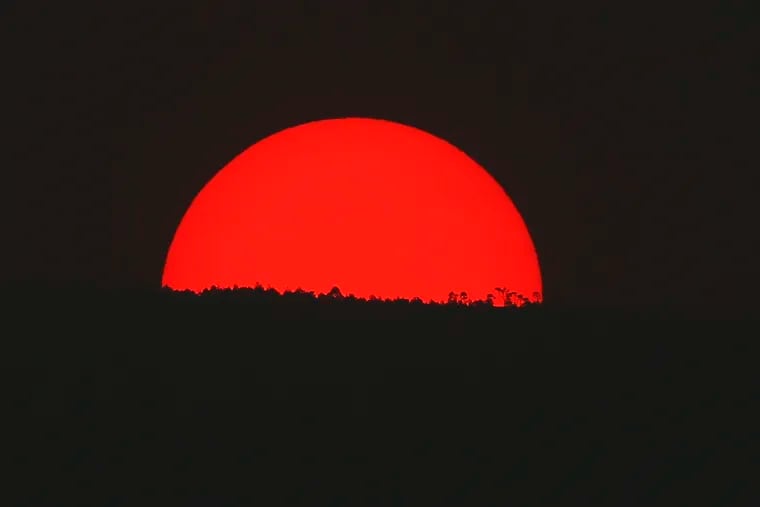 Tinted blood red by a thick cloud of smoke and pollution, the sun sets on the mountains above Mexico City, Monday, May 13, 2019. Mexico City's government has warned residents to remain indoors as forest and brush fires carpeted the metropolis in a smoky haze that has alarmed even many of those accustomed to living with air pollution. (AP Photo/Marco Ugarte)