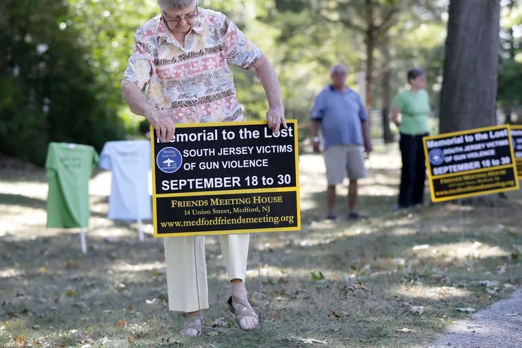 Carol Suplee of Lumberton installs a sign commemorating the victims on the grounds of the meetinghouse in Medford. The display on Union Street will be the first in South Jersey and will remain at that location for two weeks.