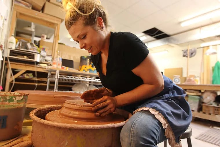 Lauren Mabry, Clay Studio resident artist is in the process of throwing a cylinder made of terracotta clay, on her pottery wheel.