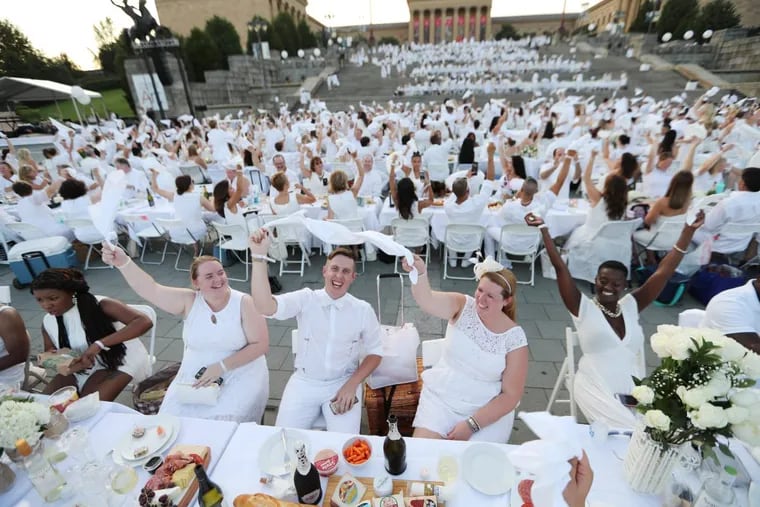 From left. Katie Filpus, Risty Prochnow, and Cathy Waugh wave their napkins at Diner en Blanc on the Art Museum steps at the start of 2016’s event.
