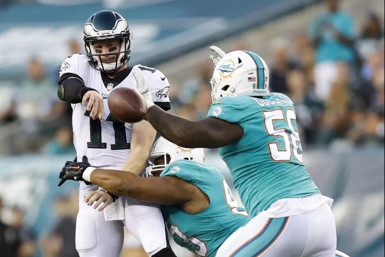 Eagles quarterback Carson Wentz gets rid of the football against Miami Dolphins defensive tackle Ndamukong Suh (center) and defensive tackle Davon Godchaux during the first-quarter in a preseason game on Thursday, August 24, 2017 in Philadelphia.