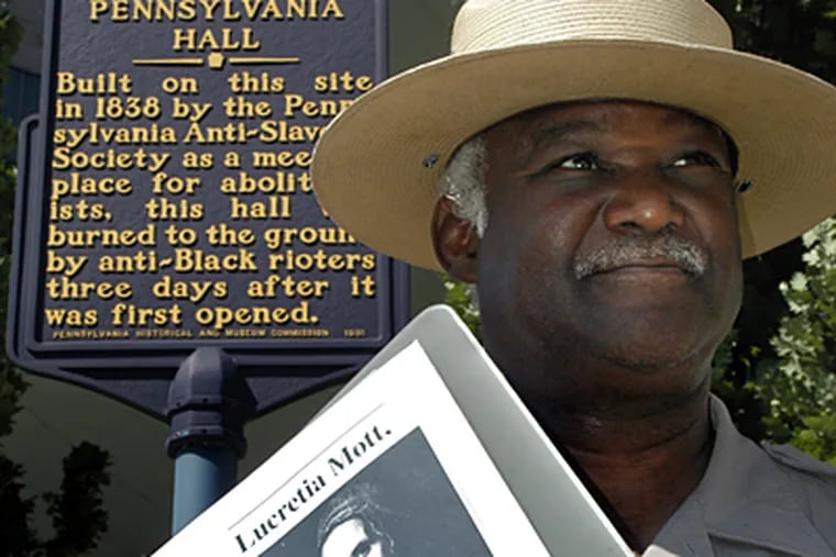 National Park Service Ranger Joe Becton with portrait of Lucretia Mott, beneath a historic marker for Pennsylvania Hall, a stops on Independence Park Underground Railroad tour. (Tom Gralish / Inquirer)