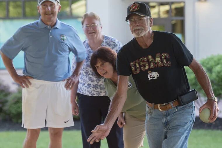 Pete Palestina, 72, rolls a bocce ball towards the pallino ball Ñ or target ball Ñ during the 8th annual game between the Northampton Township supervisors and a team from the Northampton James E. Kinney Senior Center June 19, 2018 in the bocce pavilion of the senior center. Standing in the background are Barry Moore (left), chairman of the supervisors, Janet Thomkins (center) of the senior center team and Eileen Silver, vice chairman of the supervisors. The seniors won the match for the 7th year in a row. ( Photo by Clem Murray )