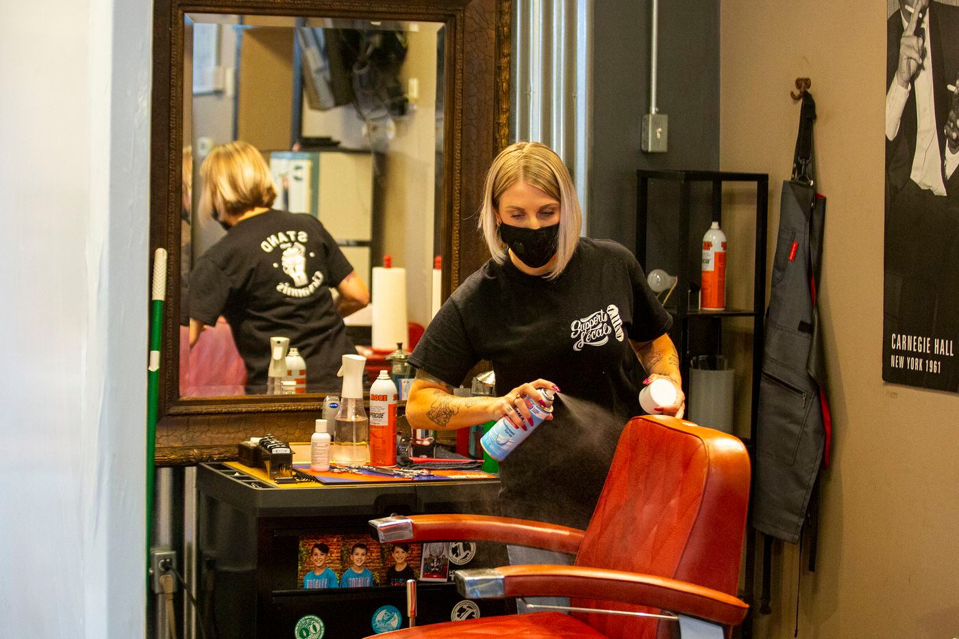 Nichole Missino, owner of Giovanni’s Media Barber Shop, disinfects a chair after cutting a customers hair on Wednesday, May 20, 2020. 