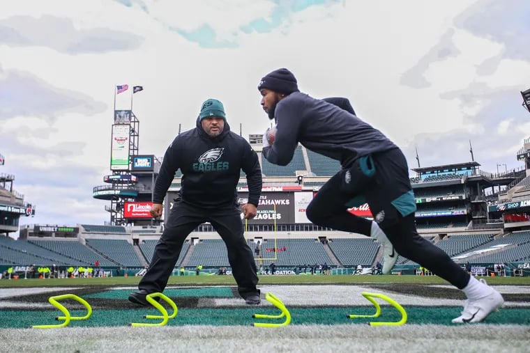 Under the watchful eye of Eagles running backs coach Duce Staley (left), Eagles running back Miles Sander  warms up in the end zone of Lincoln Financial Field  before the Wild-Card playoff game against the Seahawks on Jan. 5, 2020.