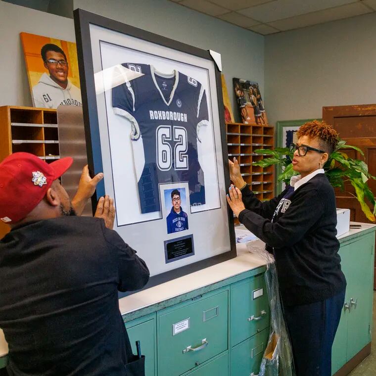 At right is Kristin Williams-Smalley, principal at Roxborough High School, with assistant principal Julian Saavedra, holding a framed football jersey and photo of Nicolas Elizalde, the Saul High School student and Roxborough football player who was killed outside the school on Sept. 27, 2022. Roxborough memorialized the anniversary of the shooting with a Day of Peace.