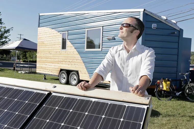 Corbett Lunsford adjusts the solar panels that help power the 200-square-foot house on wheels behind him that is making a demonstration stop in Washington Township, part of a 20-city nationwide tour.