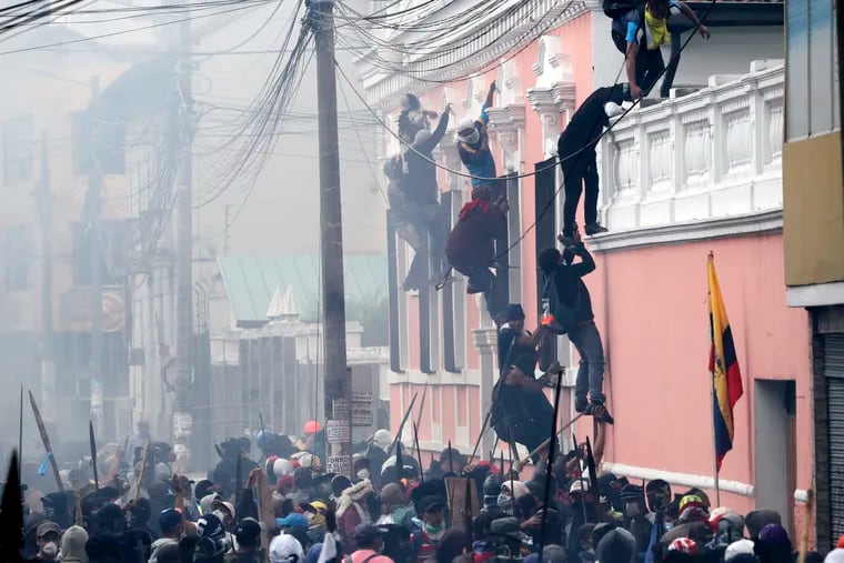Anti-government demonstrators scale the facade of a residence to reach the rooftop, looking for a better vantage point to battle with police, in Quito, Ecuador, in October 2011.