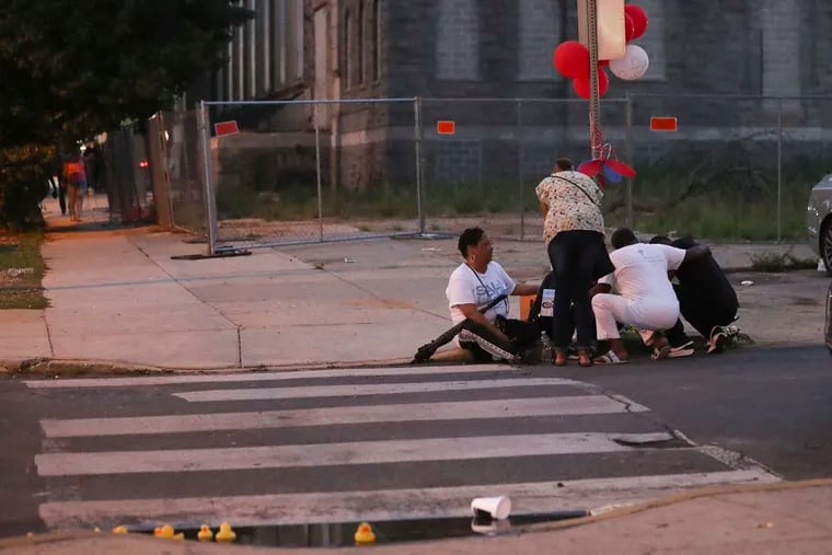 Family and community members were consoled at a memorial site on the curb of 1700 South Frazier Street in the Kingsessing section of Philadelphia on July 5.