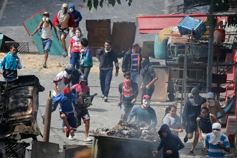 Anti-government protesters clash with security forces as they show support for an apparent mutiny by a national guard unit in the Cotiza neighborhood of Caracas, Venezuela, Monday, Jan. 21, 2019. The uprising triggered protests which were dispersed with tear gas as residents set fire to a street barricade of trash and chanted demands that President Nicolas Maduro leave power. (AP Photo/Ariana Cubillos)