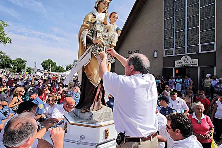 People flock to the Our Lady of Mt. Carmel statue and give money that Mount Carmel Society Treasurer Dave DeStefano of Hammonton pins on to the statue, which is always the last in the Parade of Saints at the 139th Our Lady of Mt. Carmel Festival in Hammonton on July 14, 2014.   There is a carnival, food stand, beer garden and main stage entertainment. The Mount Carmel Society calls this the longest running Italian festival in the US since 1875. ( ELIZABETH ROBERTSON / Staff Photographer )