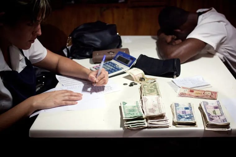 In a state-run restaurant, a worker counts her receipts and cash while a coworker rests in Havana. Recently, Cuba has been privatizing restaurants. (Bloomberg, File)