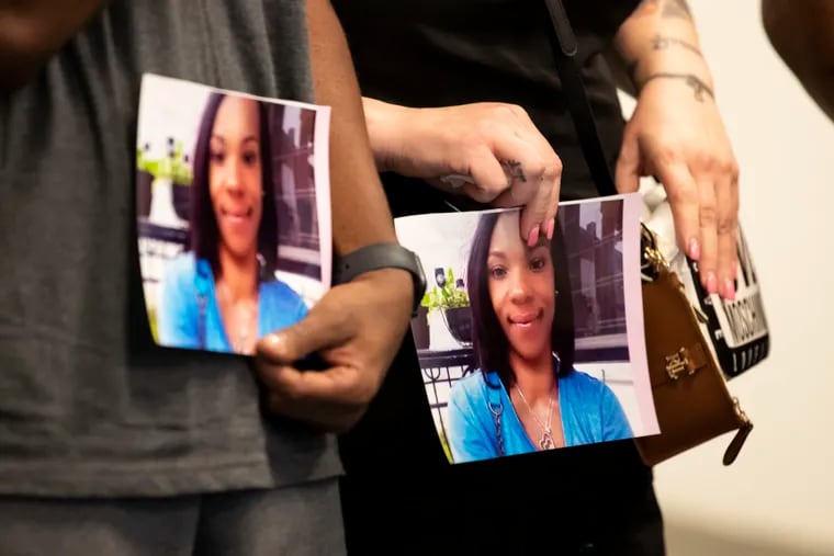 Family members hold photographs of Tiffany Fletcher, who was killed outside of the Mill Creek Recreation Center at 47th and Brown Streets.