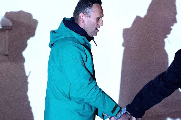 Russian opposition activist Alexei Navalny, detained upon arrival at Sheremetyevo International Airport on Jan. 17, 2021, is escorted by a police officer outside the 2nd Department of the Russian Interior Ministry Directorate for Khimki. The Khimki City Court has put Navalny in custody until Feb. 15.