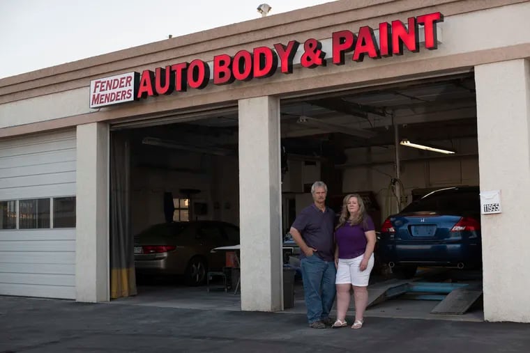 Scott and Tammy Nelson, co-owners of Fender Menders, an auto body shop, pose in front of their garage in Broomfield, Colo. The Nelsons accepted a federal PPP loan this spring.