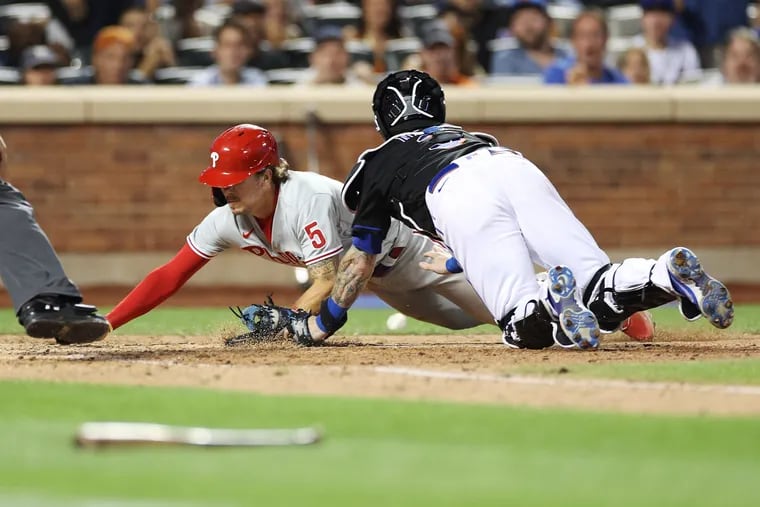 The Phillies' Bryson Stott slides past New York Mets catcher Tomas Nido to score during the 10th inning at Citi Field on Friday.