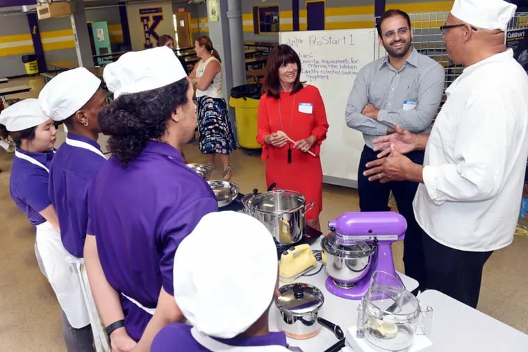 At Edna Karr Magnet High School in New Orleans (from left), Harriton High home-economics Donna Barnett and her former student, superstar chef Alon Shaya, listen to culinary teacher Kenneth Trahan discuss new equipment with students.
