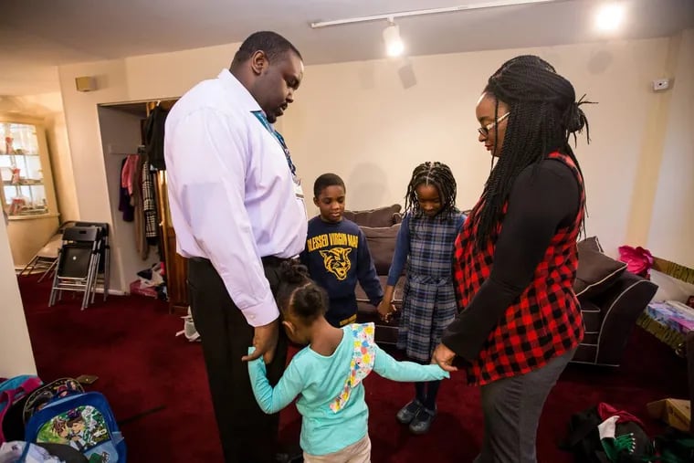Starting left, clockwise: Marques Storr Sr., 6-year-old Marques Jr., 8-year-old Naila, LaToi Storr, and 4-year-old Noelle, gather for prayer in their home prior to school. Latoi Storr and her husband started a new ritual after the Sandy Hook shooting: a huddle with the family to pray for safety throughout the day before they send the kids off to school.