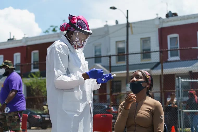 Dr. Ala Stanford, center left, founder of the Black Doctors COVID19 Consortium, shown here about to administer a coronavirus test to Tatyana Kelly, right, at a testing site run by the Black Doctors COVID19 Consortium, in partnership with the Pennsylvania Juneteenth Initiative Inc. at the Global Leadership Academy in West Philadelphia on June 19.