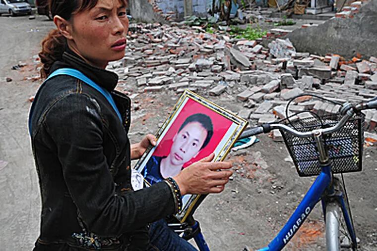 Tang Sili, 37, holds a photo of her 16-year-old son, Guo Jiaxing. He was alive for several hours after the earthquake, but was pinned by debris and died.  (Jennifer Lin/Inquirer)