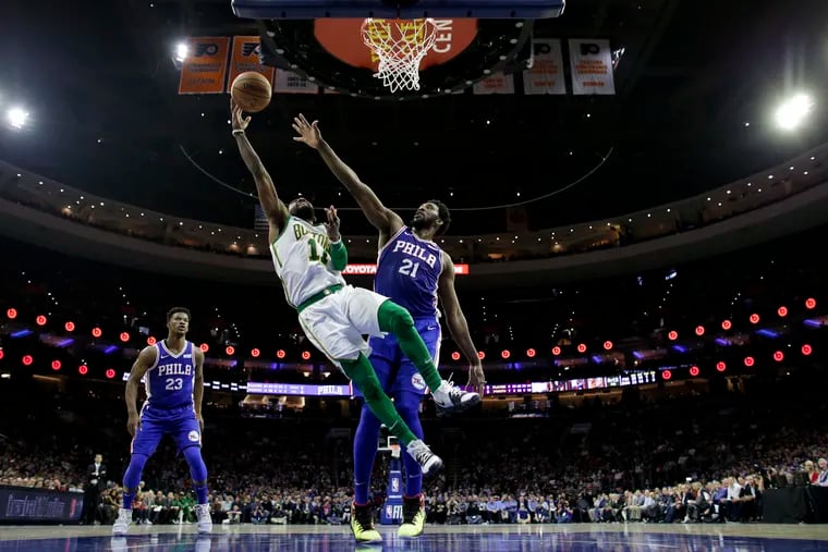 Boston Celtics' Kyrie Irving (11) goes up for a shot past Philadelphia 76ers' Joel Embiid (21) during the first half of an NBA basketball game Wednesday, March 20, 2019, in Philadelphia. (AP Photo/Matt Slocum)