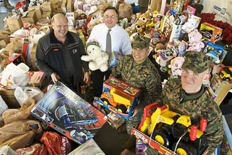 Flyers great Bob Kelly, Philadelphia Media Holdings CEO Brian Tierney, and U.S. Marines Gunnery Sgt. Daniel Gonzalez and Lance Corporal Adam Huff stand among toys donated for the 'Toys for Tots' program. (John Costello / Staff Photographer)