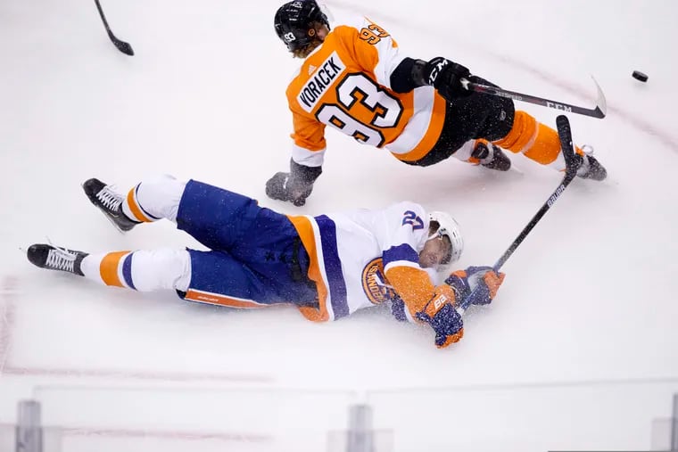 Islanders left wing Anders Lee (bottom) passes the puck as he falls to the ice near Flyers right wing Jake Voracek.