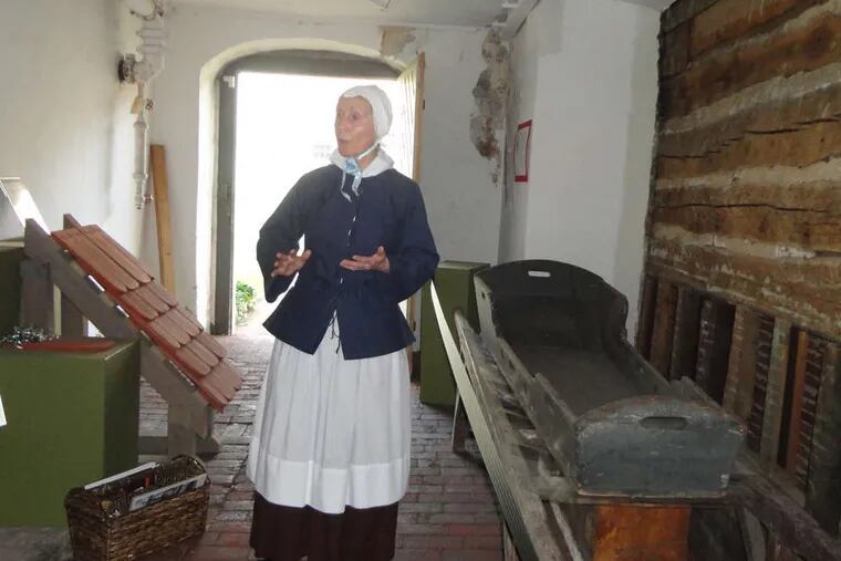 Guide Madeline Morris near a death tray (right). Moravians would &quot;live for Christ here,&quot; she said, &quot;and long for the day when you meet your savior.&quot;